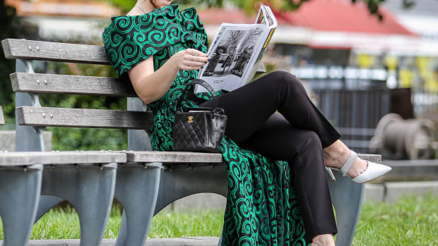 Guest is seen reading magazine wearing green and black gown with a black Chanel purse during New York Fashion Week on September 10, 2019 in New York City
