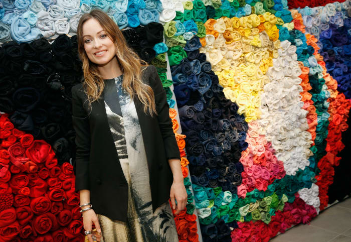 Olivia Wilde poses in front of a decorative wall of recycled T-shirts. Photo: Brian Ach/Getty Images