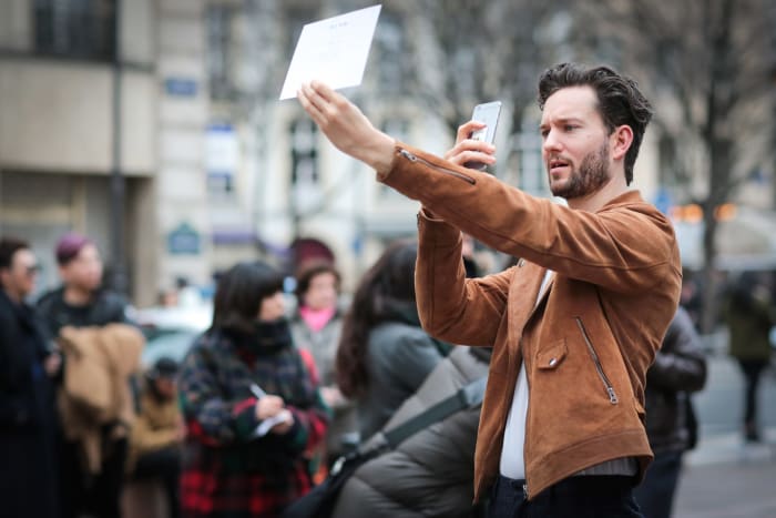 A showgoer taking a picture of his invitation during Paris Fashion Week. Photo: Edward Berthelot/Getty Images