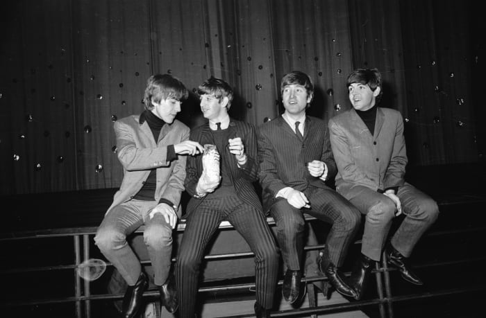 The Beatles (George Harrison, Ringo Starr, John Lennon and Paul McCartney) splitting a bag of popcorn at London's Lewisham Theatre in 1963. Photo: Terry Fincher/Express/Getty Images