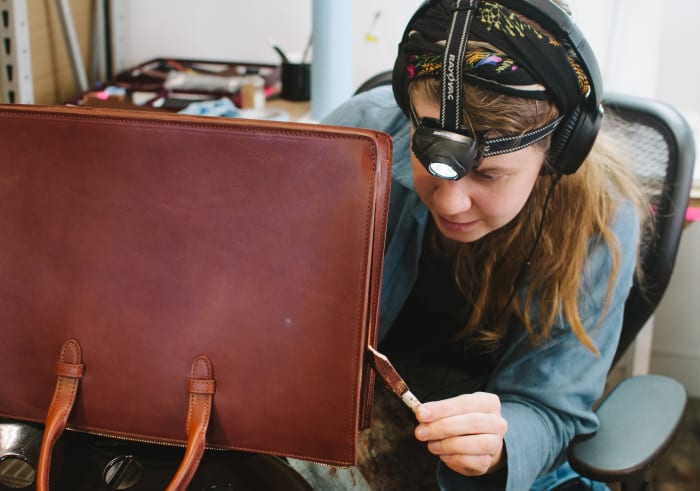 A Lotuff employee carefully paints and seals the edges of a partially-finished bag. Photo: Whitney Bauck/Fashionista