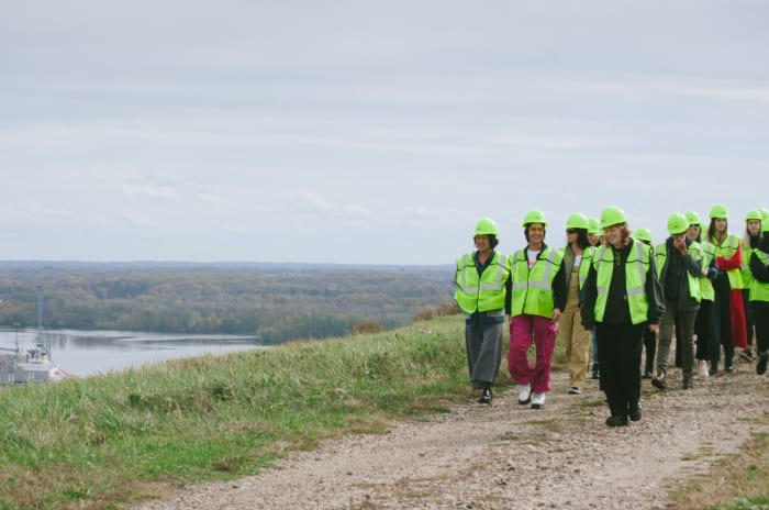 Students, clad in safety vests and hats, disembark from their tour bus at the top of a closed landfill. Photo: Whitney Bauck/Fashionista