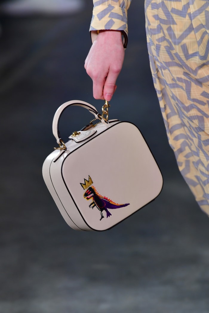 A model carrying a Coach Fall 2020 bag featuring Jean-Michel Basquiat's "Pez Dispenser".
