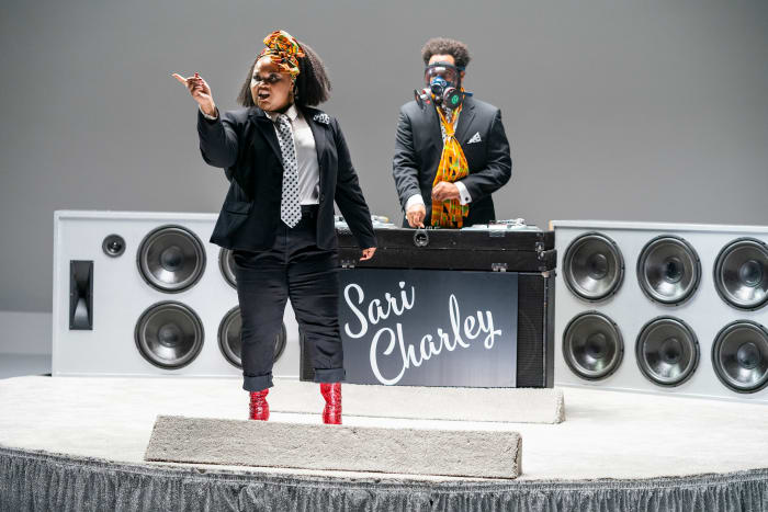 Zuri Salahuddin sings 'Add Some Kente,' while Riddle, in his custom gas mask, DJs.