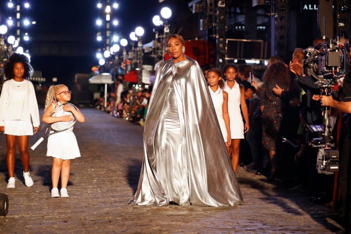 Serena Williams opens the show in a custom silver Balenciaga cape and gown, followed by four girls in white Nike outfits.