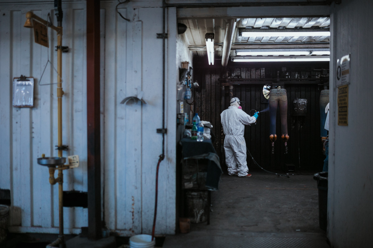 An employee spraying lightening chemicals onto jeans. Photo: Jacob Boll/Fashionista