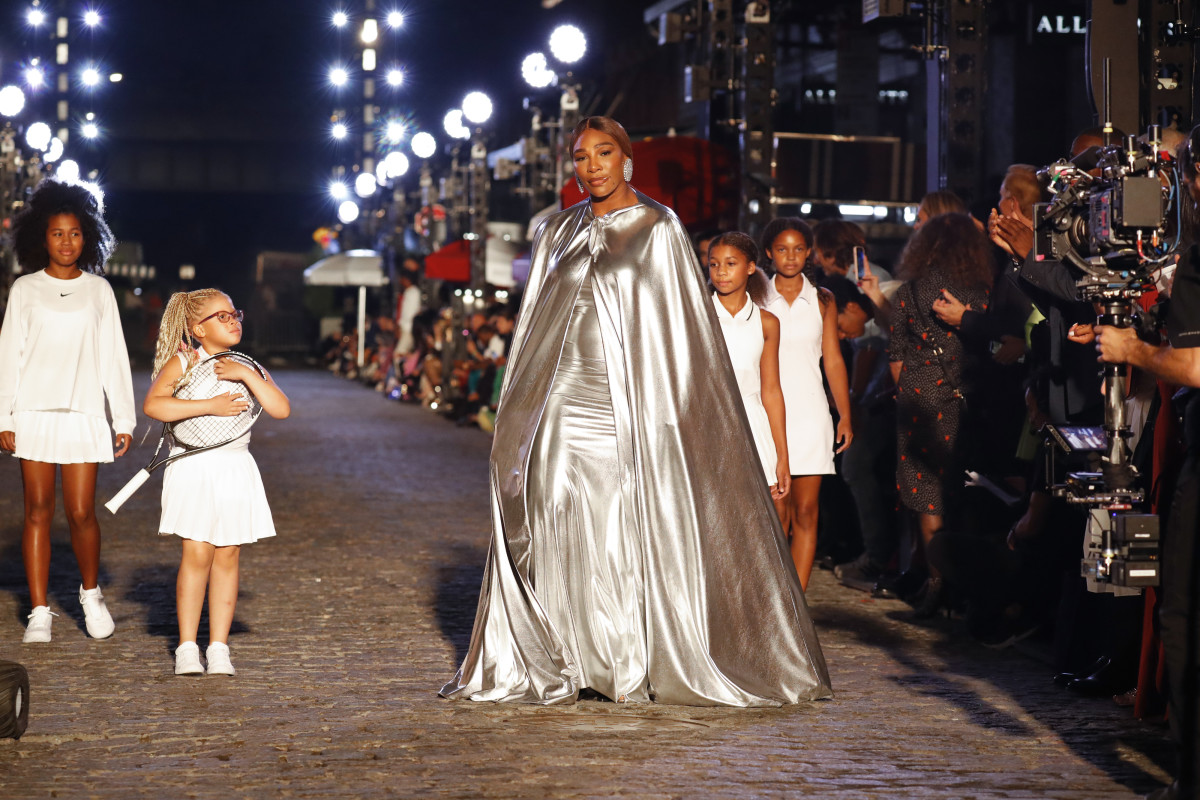 Serena Williams opens the show in a custom silver Balenciaga cape and gown, followed by four girls in white Nike outfits.